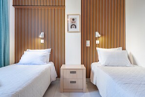 A hotel room with two beds, a nightstand, and a wall-mounted picture.