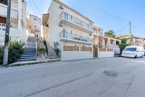 A multi-story residential building with balconies, a staircase, and a parked van. - Apartment 'Quadruple Standard Aparment 1' with Shared Terrace, Wi-Fi and Air Conditioning (Kavos)