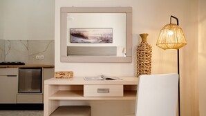 A modern kitchen with a built-in refrigerator, a wooden countertop, a white chair, a desk with a drawer, a woven vase, and a wall-mounted lamp.