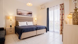 A bedroom with a bed, bedside tables, a nightstand, a dresser, a hanging light, a painting, and a window with curtains.
