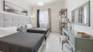A bedroom with two beds, a dresser, a mirror, and a painting on the wall.