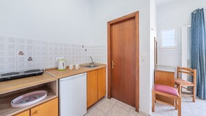 A compact kitchen with a dishwasher, a sink, and a wooden door.