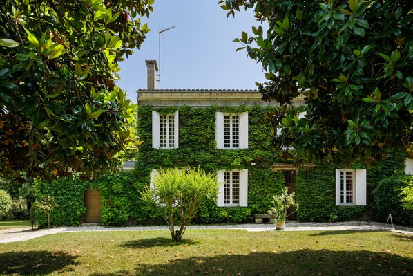 A building with ivy-covered walls, white shutters, and a clear sky.