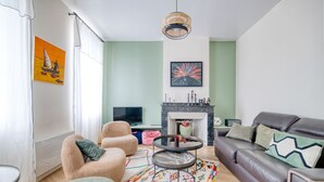 Ein Wohnzimmer mit einer Couch, Sesseln, einem Couchtisch, einem Kamin und Kunstwerken an den Wänden.