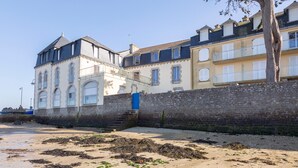 A coastal building with a stone wall, a blue door, and a balcony.