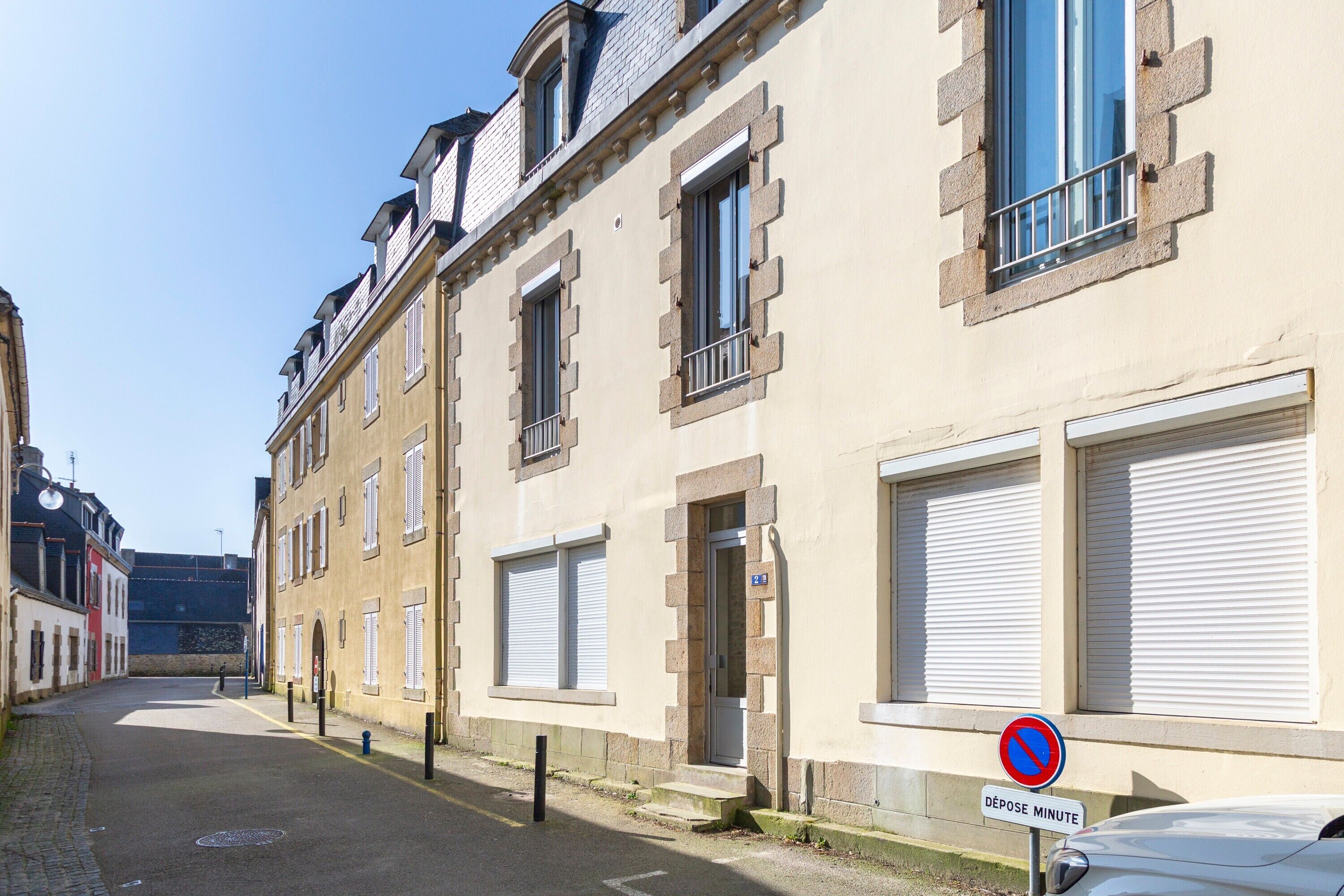 A narrow street with buildings, a no parking sign, and a 'Dépose Minute' sign.