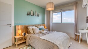 Un dormitorio con cama, mesitas de noche, un escritorio y una ventana con cortinas.