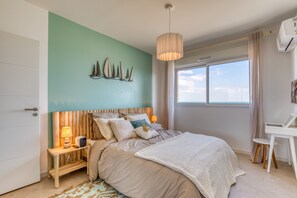 Un dormitorio con cama, mesitas de noche, un escritorio y una ventana con cortinas.
