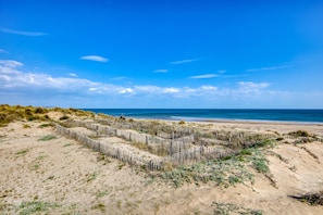 Une plage de sable avec une clôture en bois et des dunes.