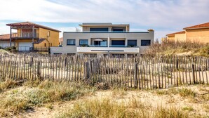 Una casa moderna de dos pisos con techo plano, balcón y patio cercado.