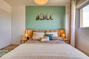 Une chambre à coucher avec un lit, des lampes de chevet, une œuvre d’art murale et une fenêtre.