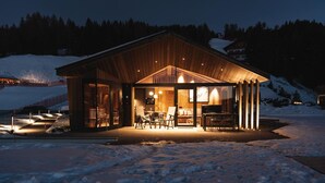 A wooden cabin with a glass-enclosed porch, a dining area, and a seating area. - Chalet 'Ski' on the slopes with mountain view, private terrace, and Wi-Fi (Selva di Val Gardena)