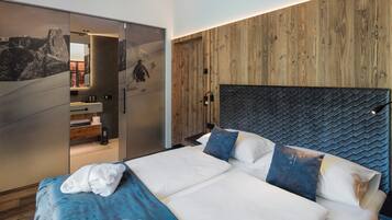 Quarto moderno com uma cama grande, cabeceira de madeira e porta deslizante que dá para um banheiro.