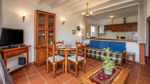 A dining area with a wooden table and chairs, a television, and a cabinet. - Apartment 'Casa Doce' with Shared Pool, Wi-Fi and Air Conditioning (Alvor)