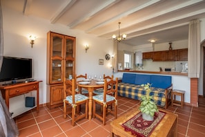 A dining area with a wooden table and chairs, a television, and a cabinet.