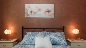 Een slaapkamer met een bed met een patroongordijn, een wit kussen en twee bedlampen.