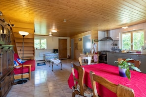 A cabin interior with a dining area, kitchen, and a staircase.