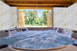Un jacuzzi con vista a árboles y una estructura de madera en el exterior.