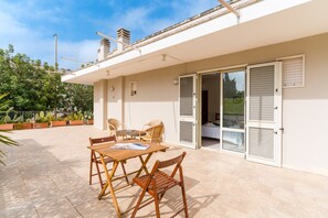 Il s’agit d’une propriété résidentielle dotée d’un patio, de mobilier d’extérieur et d’une porte-fenêtre coulissante donnant sur une pièce intérieure.