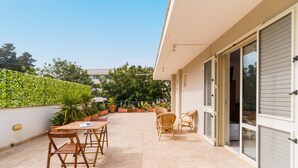 An outdoor patio with a table and chairs, potted plants, and a building entrance. - Room 'Cassiopea' with Shared Terrace, Wi-Fi, and Air Conditioning (Otranto)