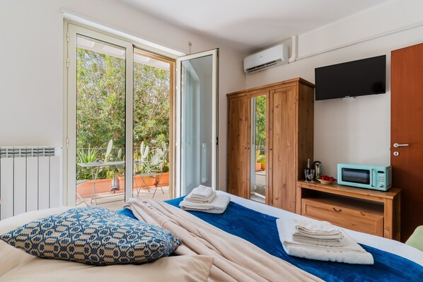 A bedroom with a bed, a wooden wardrobe, a TV, and a microwave.