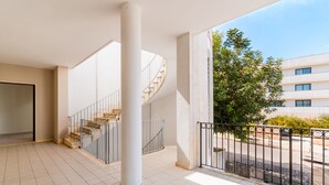 A spacious indoor area with a spiral staircase, large pillars, and a view of a building and trees. - Room 'Berenice' with Shared Terrace, Wi-Fi, and Air Conditioning (Otranto)