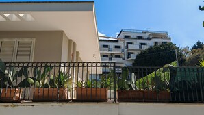 A residential building with a white facade, a balcony with metal railings, and potted plants. - 'Fenice' Room with Shared Terrace, Wi-Fi, and Air Conditioning (Otranto)