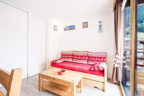 Une pièce avec un canapé en bois, une table en bois et une vue à travers une porte vitrée.