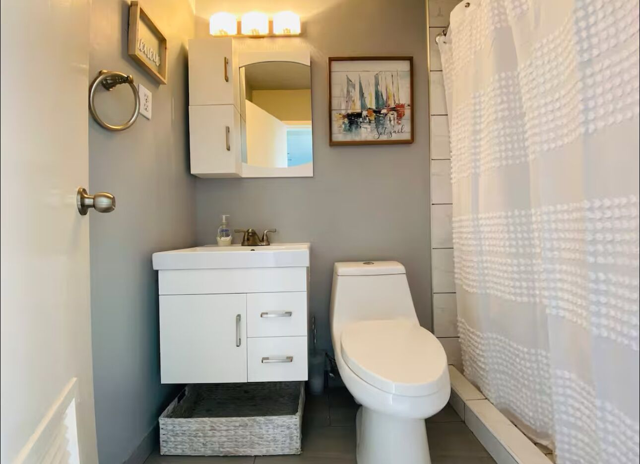 A bathroom with a white toilet, a sink with a mirror above it, and a shower curtain.