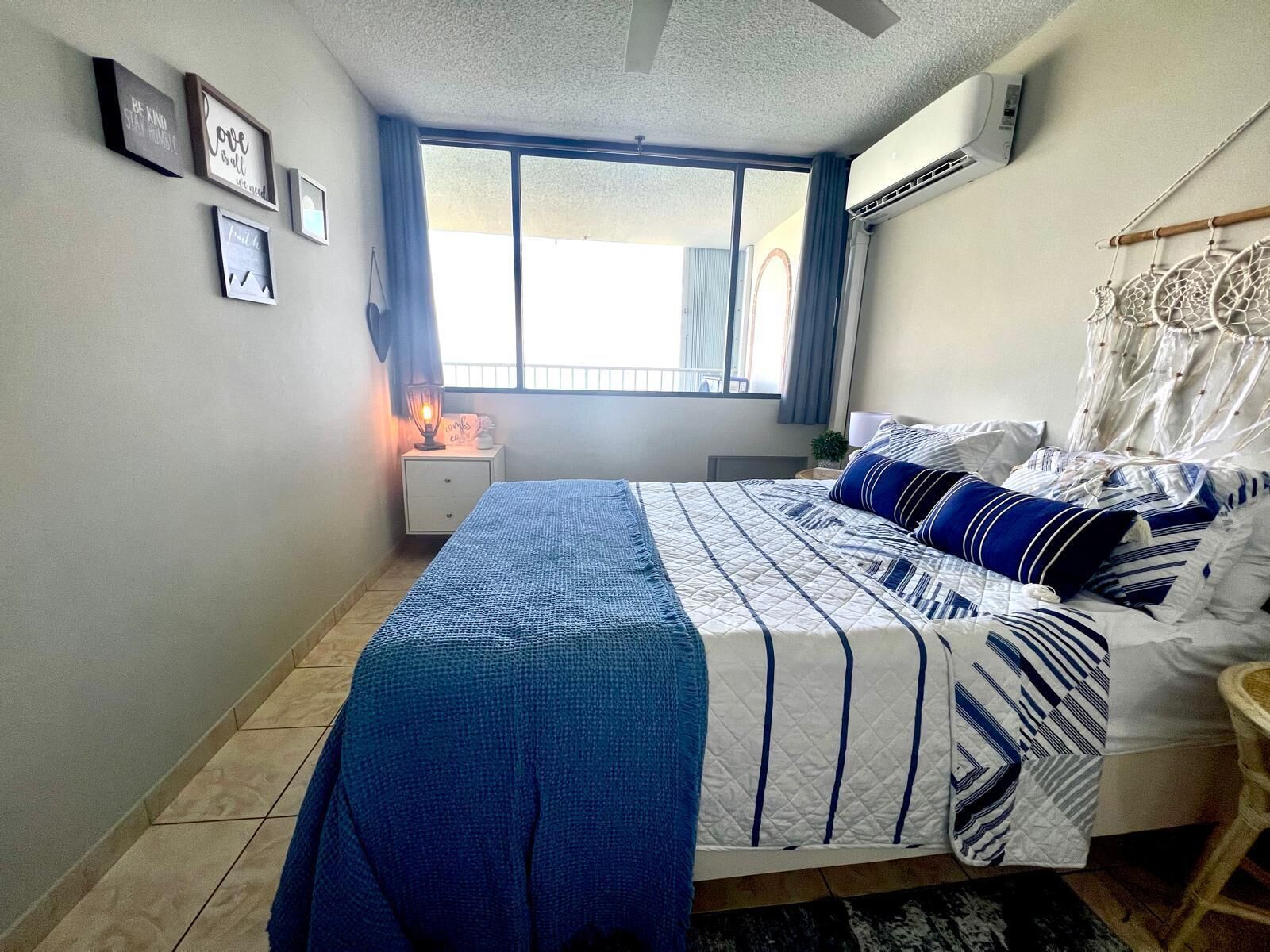 A bedroom with a bed, a nightstand, a window, and wall decorations.