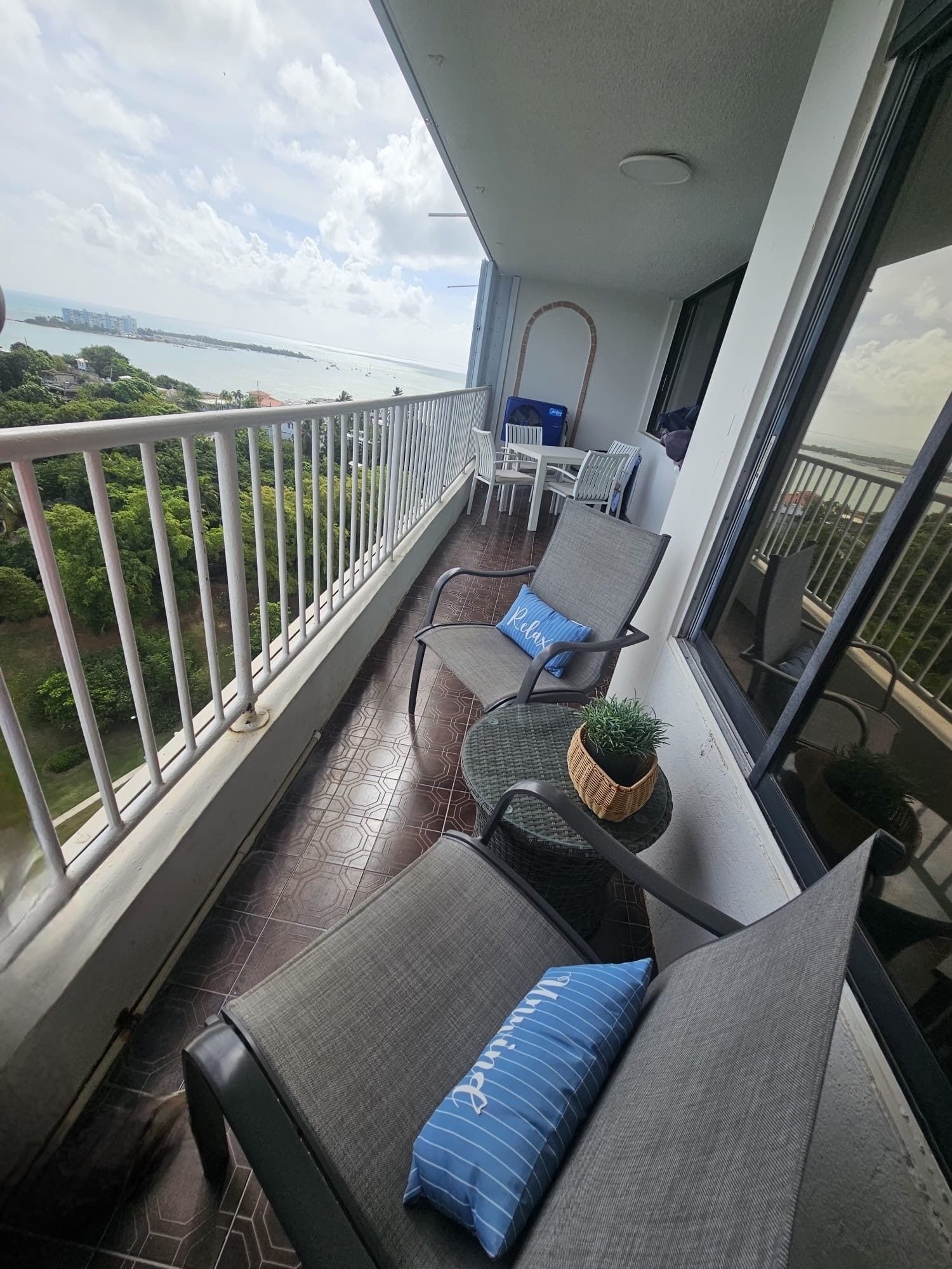 Ein Balkon mit Meerblick, einem Tisch, Stühlen und einem Blumentopf.