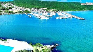 A marina with boats docked, a swimming pool, and a hillside in the background. - Condo with Amazing Ocean View in Fajardo near Villa Marina (Fajardo)