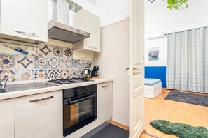 Una cocina compacta con estufa, horno y azulejos modernos.