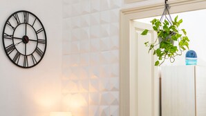 Une pièce avec une horloge murale, une plante suspendue et une lampe.