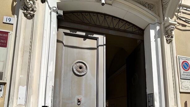 Une entrée d’immeuble avec une grande porte, une caméra de surveillance et un panneau indiquant qu’il est interdit de se garer.