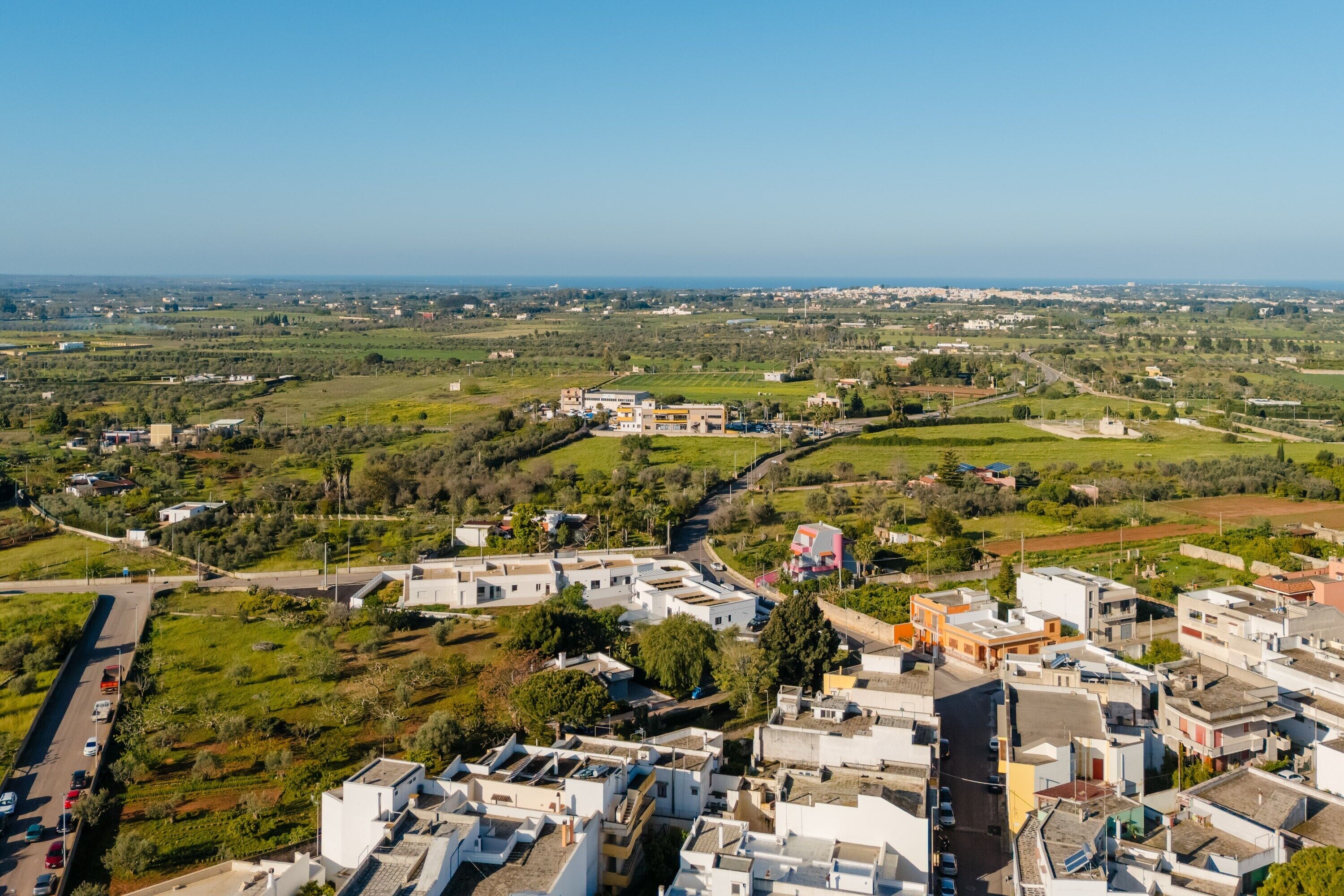 Vista aérea de una zona residencial con edificios, carreteras y campos verdes.