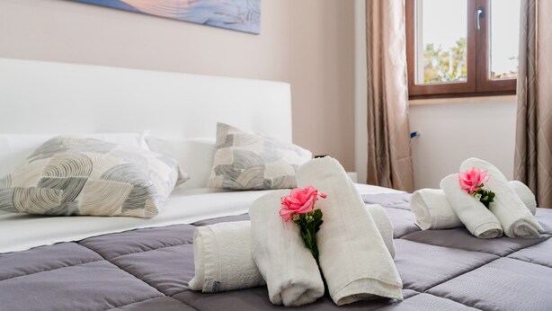 Un lit bien fait, avec des oreillers, une fenêtre avec des rideaux et un tableau accroché au mur.