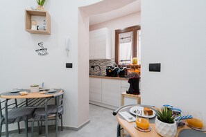 Una cocina compacta con comedor, una estantería con adornos y un adhesivo en la pared.