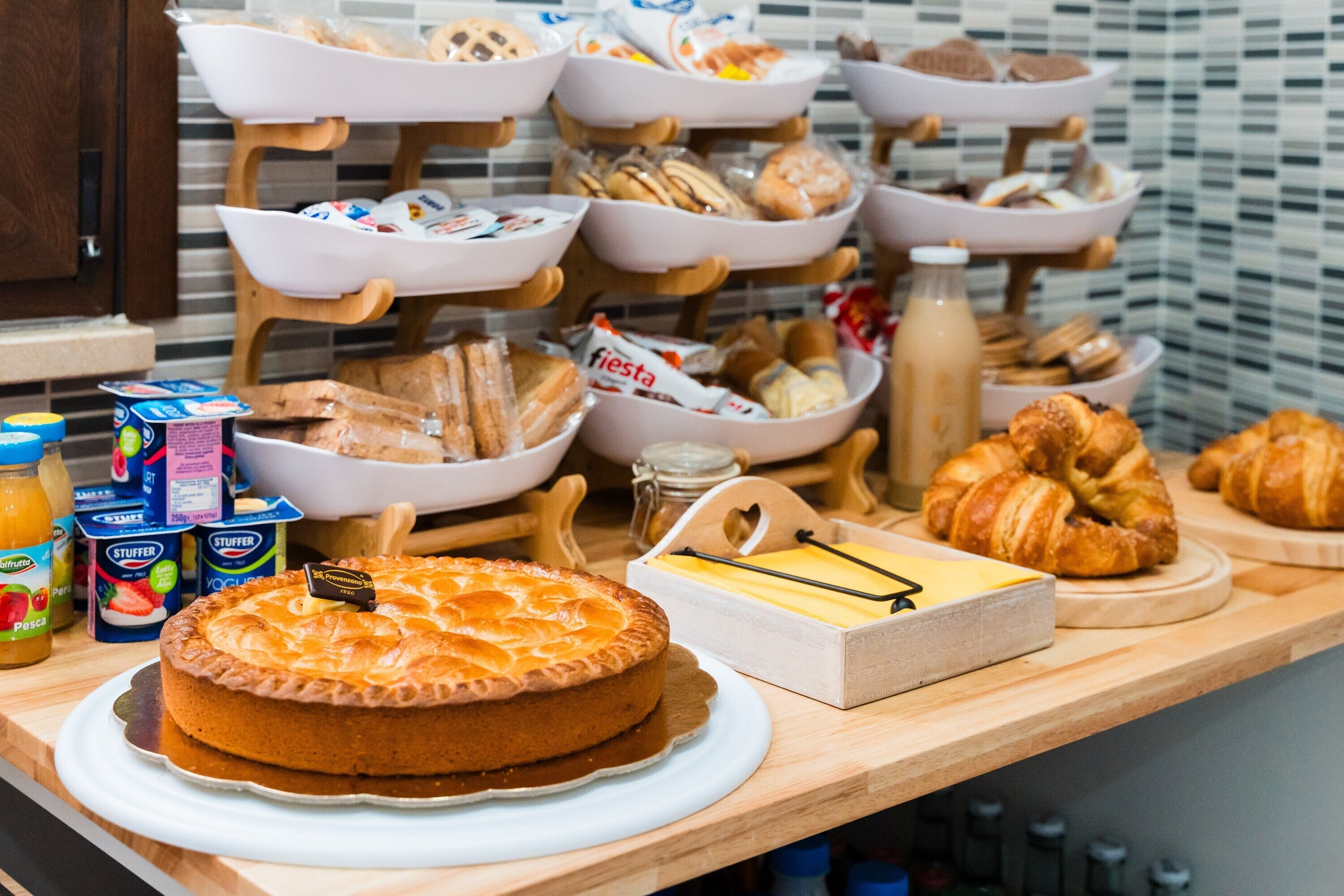 A buffet with various food items including a pie, pastries, and condiments.