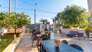 Un espace extérieur aménagé en terrasse, avec des tables et des chaises, un vase décoratif et un grand arbre.