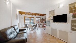 Un salon comprenant un canapé, un téléviseur et un coin repas avec des chaises et une table.