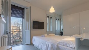 A bedroom with a bed, bedside tables, a TV, and a window with a view.