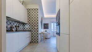 A modern kitchen with white cabinets, a patterned backsplash, and a small dining area with a table and chairs.