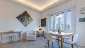 A modern living room with a dining table, chairs, a sofa, and artwork on the walls.