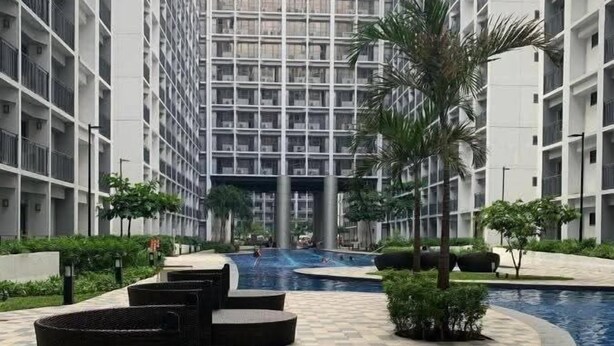 A modern residential building with a central swimming pool, surrounded by outdoor seating areas and greenery.