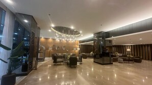 A spacious lobby with a modern chandelier, comfortable seating, and a glass partition.