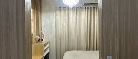 Una camera d'albergo con un letto, una toeletta con specchio e un lampadario.