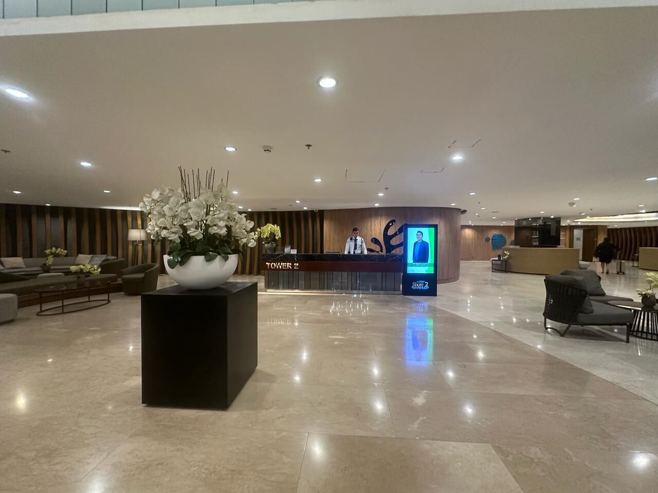 A spacious lobby with a reception desk, a large floral arrangement, and a modern reception area.