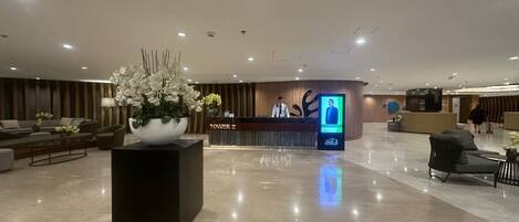 A spacious lobby with a reception desk, a large floral arrangement, and a modern reception area.