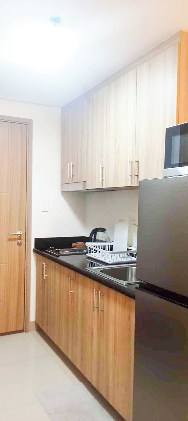 A kitchen with wooden cabinets, a stainless steel refrigerator, a microwave, a stove, and a dishwasher.